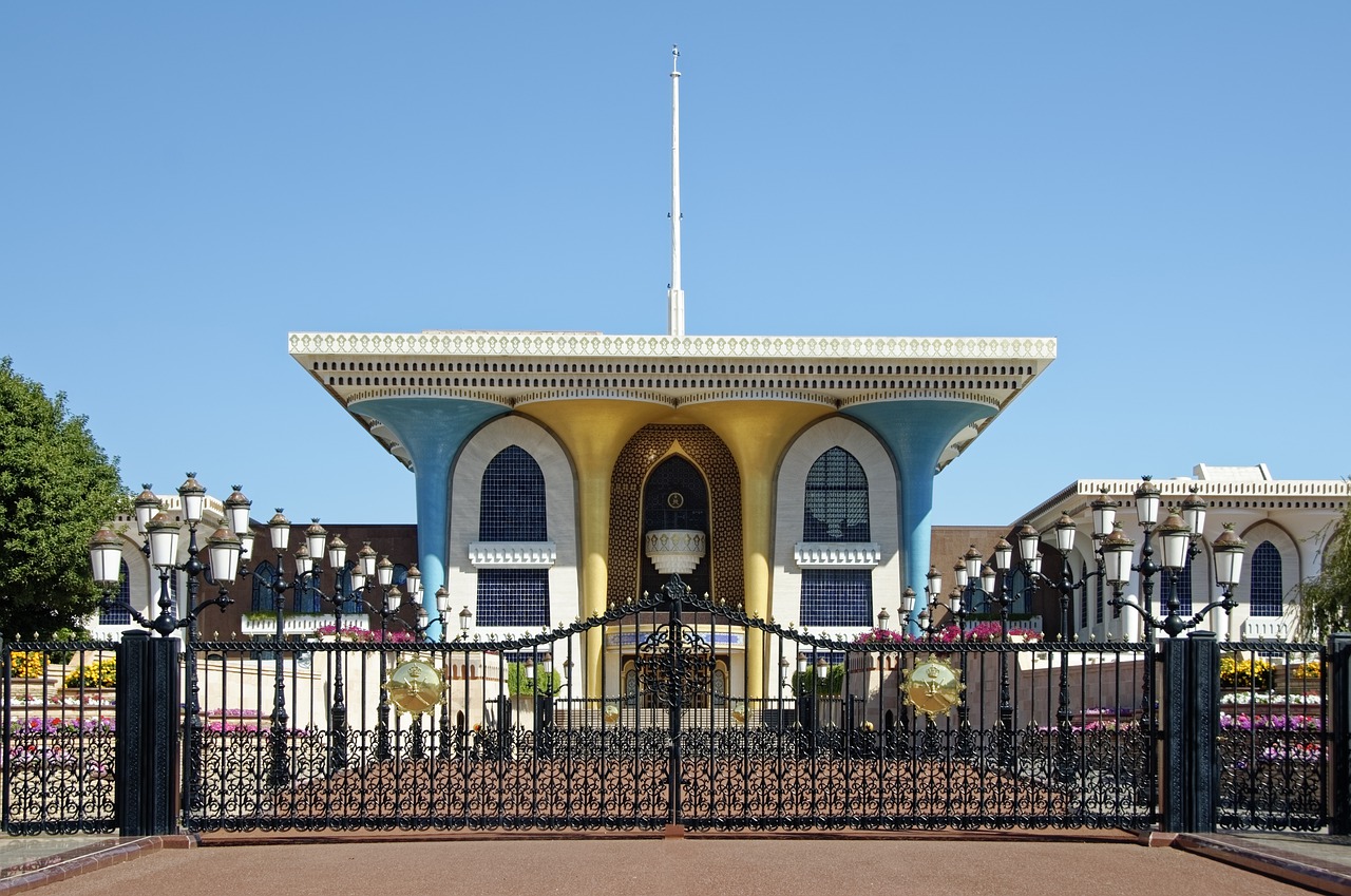 yellow-blue small palace with flat roof surrounded by black fence