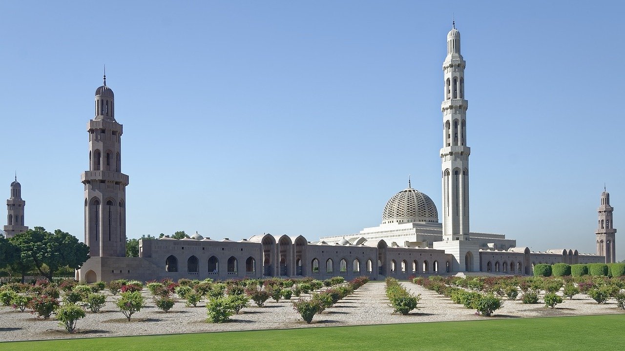 white mosque from far away with 2 high towers and a big dome