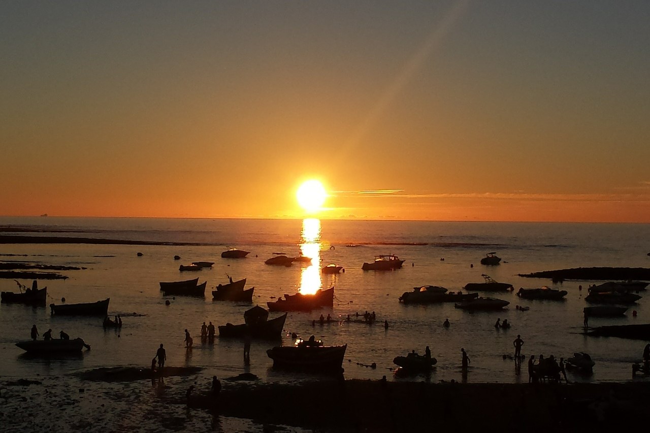 Sunset over sea with many small ships on it